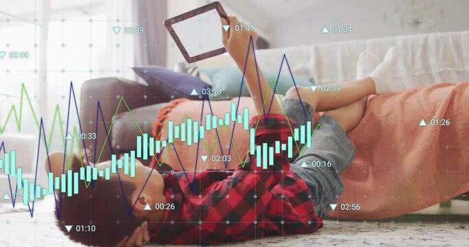 Chinese boy lifting tablet lying next to sofa and scrolling showing charts for technology demo