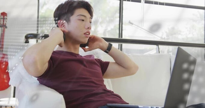 Technology student coding on couch and activating animated code overlay while adjusting headphones