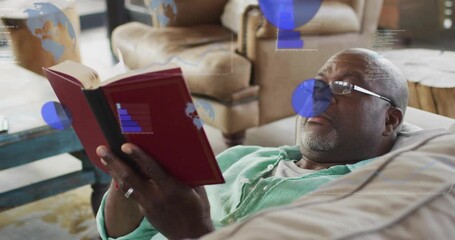 Senior man reclining on sofa scanning red book while technology charts, code appearing then fading - Powered by Adobe