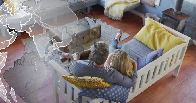 Couple shifting cushions on daybed while emerging globe rotating highlighting regions in technology