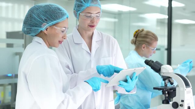 In a clinical research facility, scientists perform data validation, comparing results on a tablet with the standard operating procedure SOP for a new pharmaceutical drug trial.