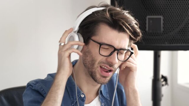 Young man in sound recording studio. Close up of guy's head listening to music through headphones. Enjoying process of recording.