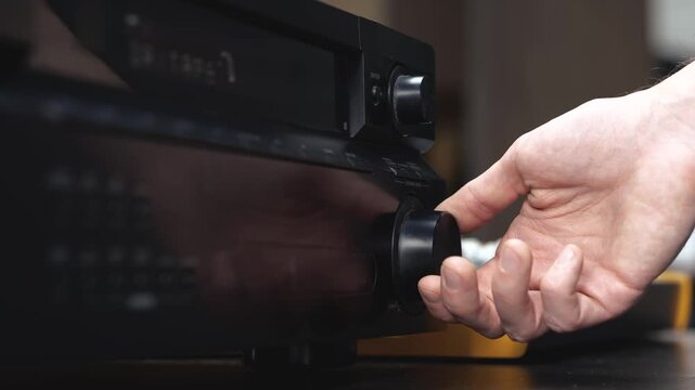 Young man in sound recording studio. Cut view video of man's hand reaching music console and changing volume.