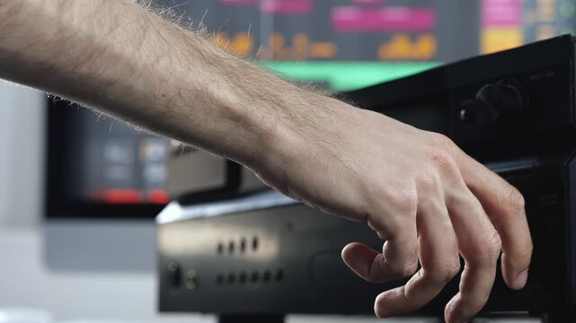 Young man in sound recording studio. Slow motion of hand reaching music consol. Changing volume. Close up video.