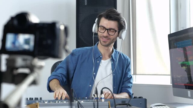 Young man in sound recording studio. Guy video blogger greets and start using music mixing console. Show how to work with professional sound equipment.