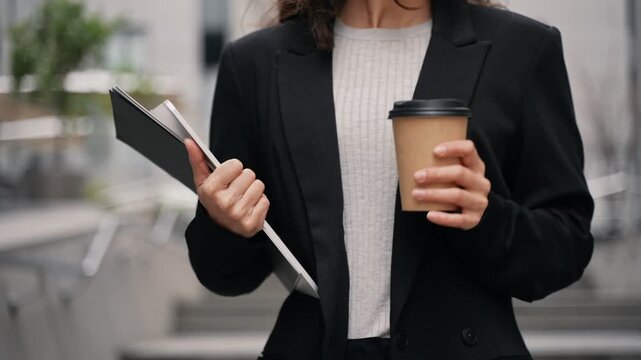 Young businesswoman walking downstairs in offices aria with tall contemporary buildings. Close-up, slow motion. outdoors, work remotely, business environment.
