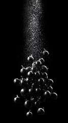 Dramatic black and white macro of fresh elderberries falling into water creating a splash of tiny droplets and bubbles