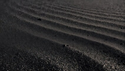 Naklejka premium Close-up shot reveals textured ripples in black sand, reflecting subtle light