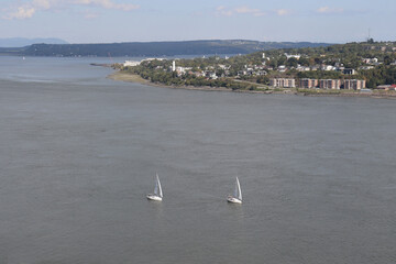 Sailing boats in a vast river and the riverside of Levy in Quebec aera. Cityscape with the St-Laurent river. Quebec and Canada landscape. Horizon and panorama of the south riverside of Quebec.