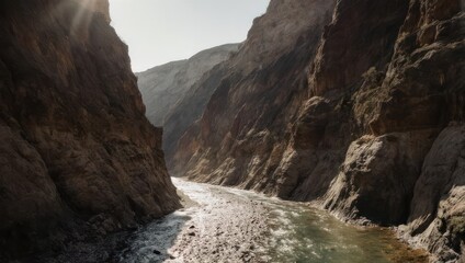 Deep canyon carved by a flowing river, sunlit, rocky walls rising above