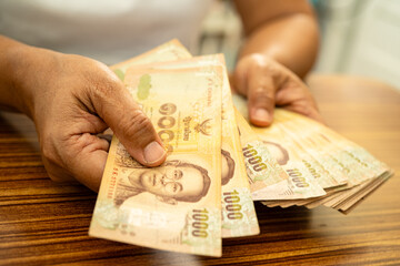 Asian business woman holding Thai banknote currency money.