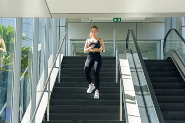 Exercise woman sport workout fit individual descends stairs, engaging outdoor physical exercise for wellness, modern urban architecture frames activity