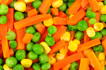 Cooked mixed vegetable background detail including carrots, peas and sweetcorn