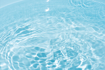 Obraz premium Blue water with ripples on the surface. Defocus blurred transparent blue colored clear calm water surface texture with splashes and bubbles. Water waves with shining pattern texture background.