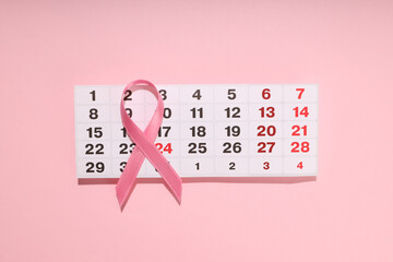 Pink ribbon placed on a calendar highlighting October dates