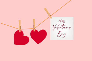 A pink background with two red hearts and a "Happy Valentine's Day" card hanging on a string with clothespins.