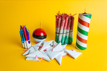  Composition of a variety of festive pyrotechnics, including rockets, a sphere, and triangular firecrackers, on a vibrant yellow background.
