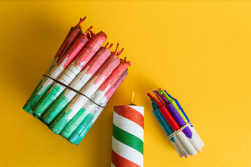 Top view of two bundles of firecrackers tied with rubber bands and a large striped explosive on a bright yellow background.
