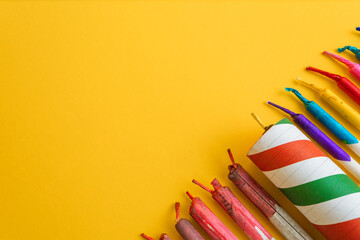 Diagonal composition of a variety of bright, colorful fireworks and firecrackers, leaving ample copy space on a yellow background.