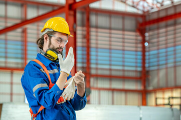 A construction worker is putting on his gloves.