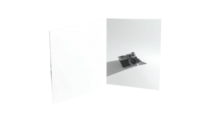A camera rests in the corner of white folded paper casting a shadow