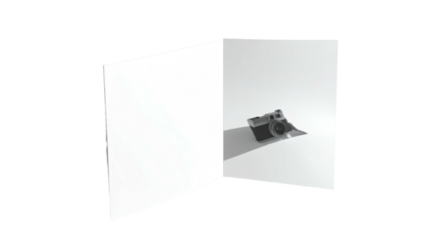 A camera rests in the corner of white folded paper casting a shadow
