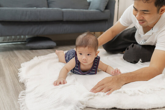 A father spends quality time with his baby, playing and bonding through gentle care and fun moments on a soft mat. The baby explores tummy time and pacifier use with support.