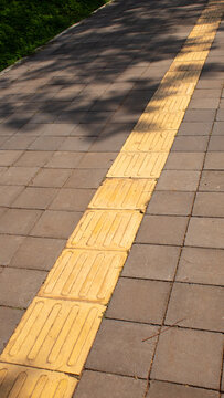 Yellow Tactile Paving Path on City Sidewalk
