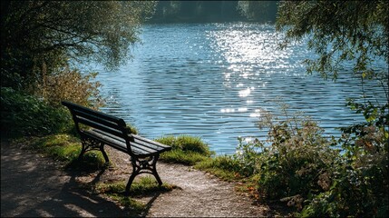 A serene park scene featuring a rustic bench positioned near a tranquil body of water. The bench, made of dark wood and metal, casts a gentle shadow on a winding path surrounded by lush greenery. Sunl