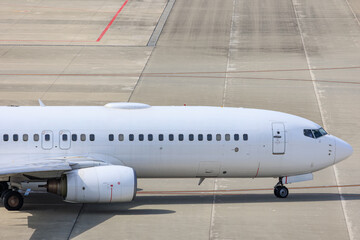 Obraz premium Close-up view of a commercial airplane cockpit and nose section at an airport. A pilot is preparing for flight, representing the aviation and travel industry.