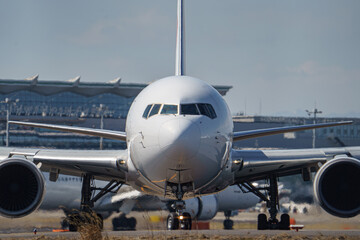 Close-up view of a commercial airplane cockpit and nose section at an airport. A pilot is preparing for flight, representing the aviation and travel industry.
