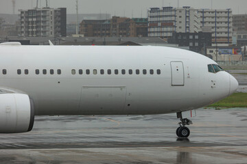 Close-up view of a commercial airplane cockpit and nose section at an airport. A pilot is preparing for flight, representing the aviation and travel industry.