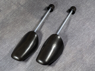 Black plastic shoe trees. Shoe stretcher on a gray background. Shoe care and storage    