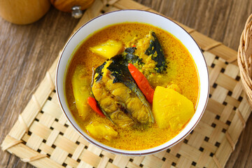 A rich and flavorful bowl of Pindang Ikan, a traditional Indonesian soup featuring tender fish, pineapple and chili in a clear, sour, and spicy yellow broth.