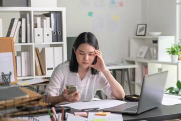 Young Asian Businesswoman looking stressed while talking on the phone, Young businesswoman working at office feels overworked and burnout