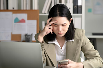 Young Asian Businesswoman looking stressed while talking on the phone, Young businesswoman working at office feels overworked and burnout