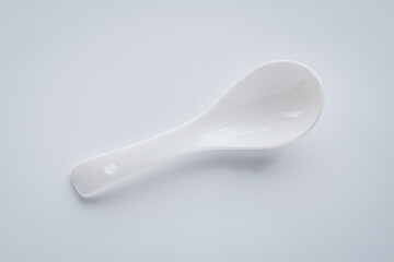 Minimalist overhead shot of a ceramic spoon used for soups, isolated on white.