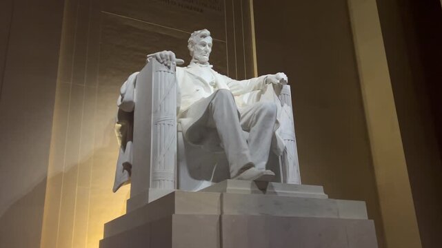 Abraham Lincoln Memorial Statue in Washington D.C. with night lighting. The marble statue of the U.S. Civil War President is viewed at an angle with a with steady zoom in.