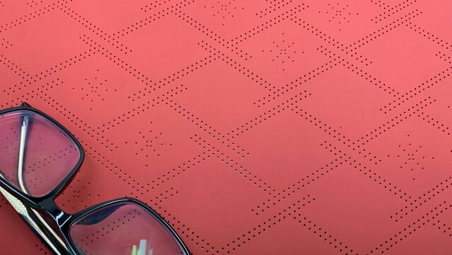 Modern glasses on a vibrant red textured surface for sleek design or eye care advertisement - Powered by Adobe