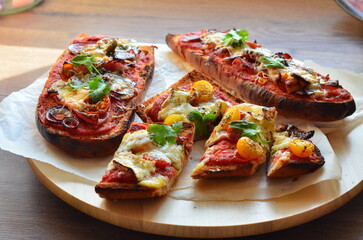 Close-up view of traditional Polish fast food zapiekanka with tomato sauce, melted cheese, and fresh vegetables. The colorful background highlights the vibrant and appetizing street food popular