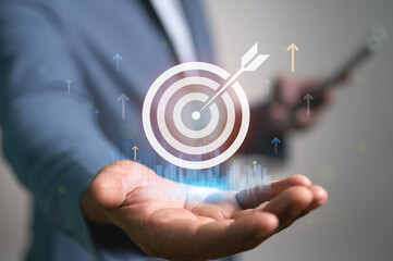 Businessman holding a virtual target icon with an arrow in the bullseye. This symbolizes achieving business goals, marketing objectives, and successful strategy, leading to growth and success.