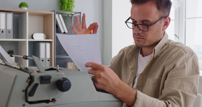 Writer and editor holding pencil to edit text typing on vintage typewriter. Busy author sitting at desk to review document and research manuscript, proofreading with concentration and productivity