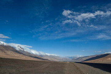 Vast desert landscape with snow-capped mountains under a clear blue sky