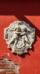 Cherubic Relief on Weathered Red Wall - Architectural Detail.