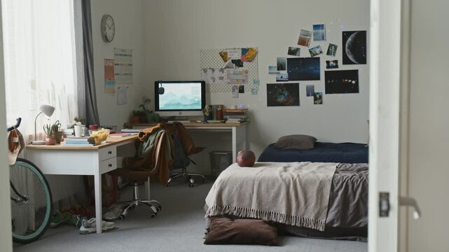 From doorway shot of messy teenage boys room with twin beds and computer on desk, no people, copy space