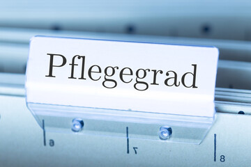 Schild mit der Aufschrift PFLEGEGRAD an einem Hängemappenregister