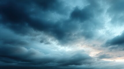 A dramatic sky filled with dark, swirling clouds, showcasing shades of blue, gray, and hints of light from the horizon.