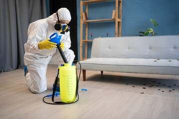 Male exterminator killing cockroaches in house. Elderly man in protective suit and respirator mask...