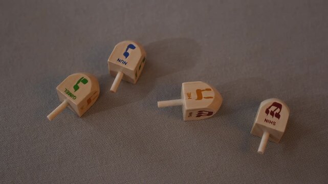 No people close up shot of four dreidels with engraved letters of Hebrew alphabet prepared for playing during Hanukkah celebration
