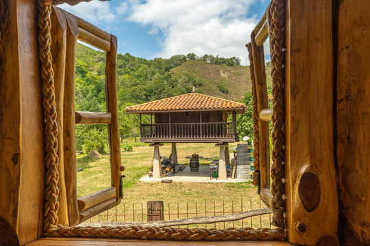 Open wooden window overlooking traditional elevated granary in rural asturias, spain